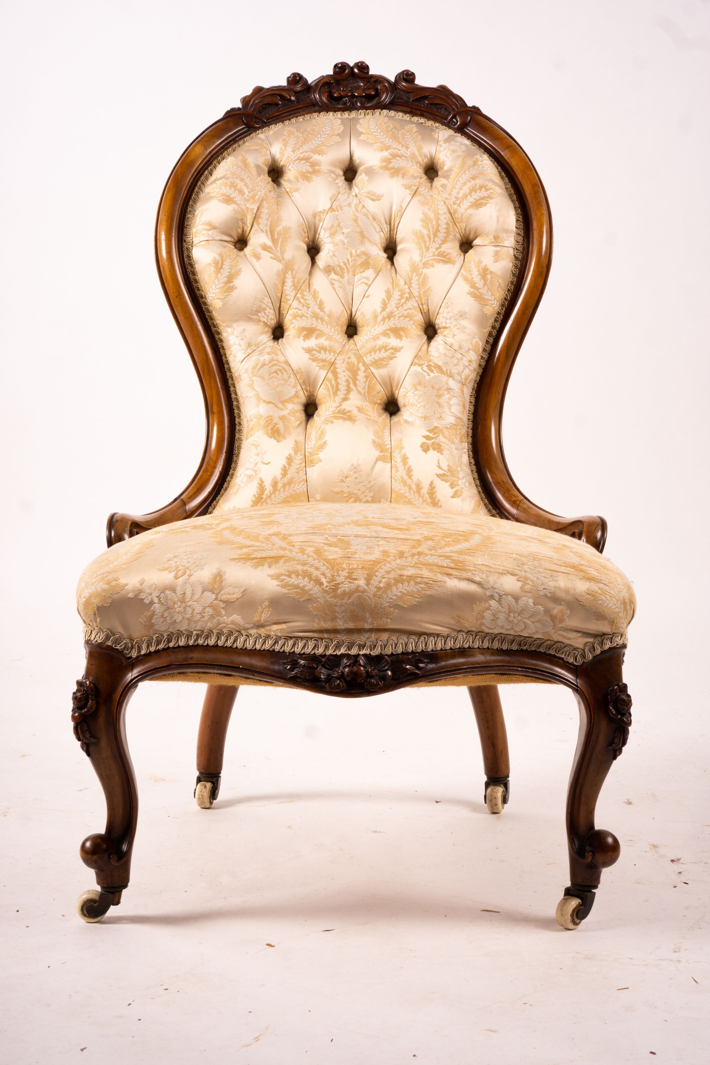 A late Victorian carved walnut three piece salon suite, comprising chaise longue, open armchair and nursing chair